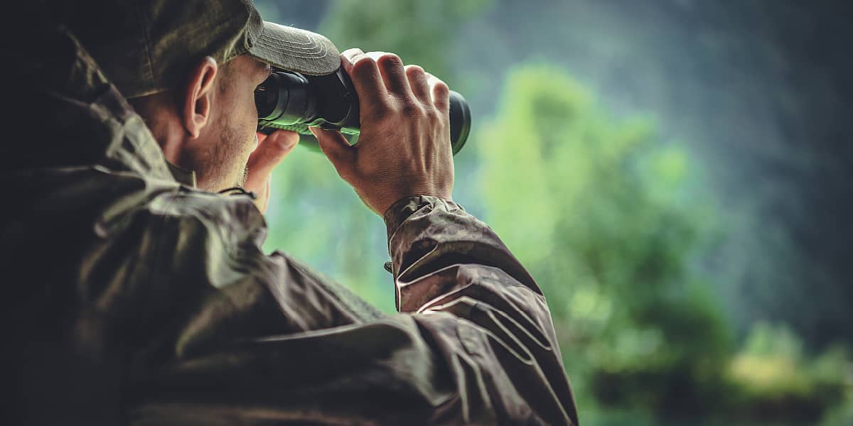 A man looking into binoculars